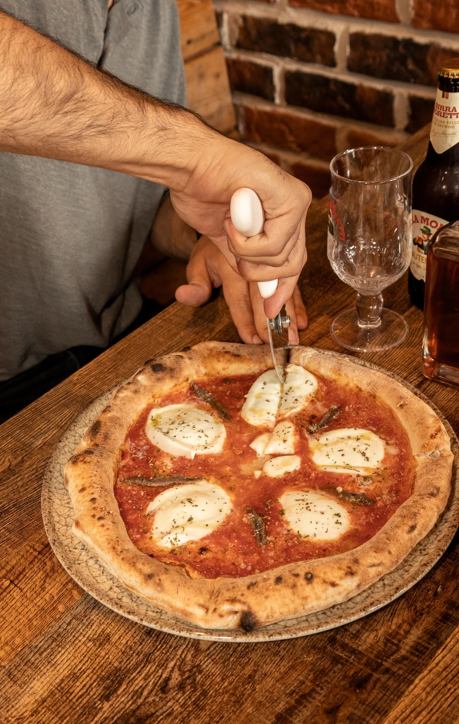 Margherita-style pizza being cut at the bar