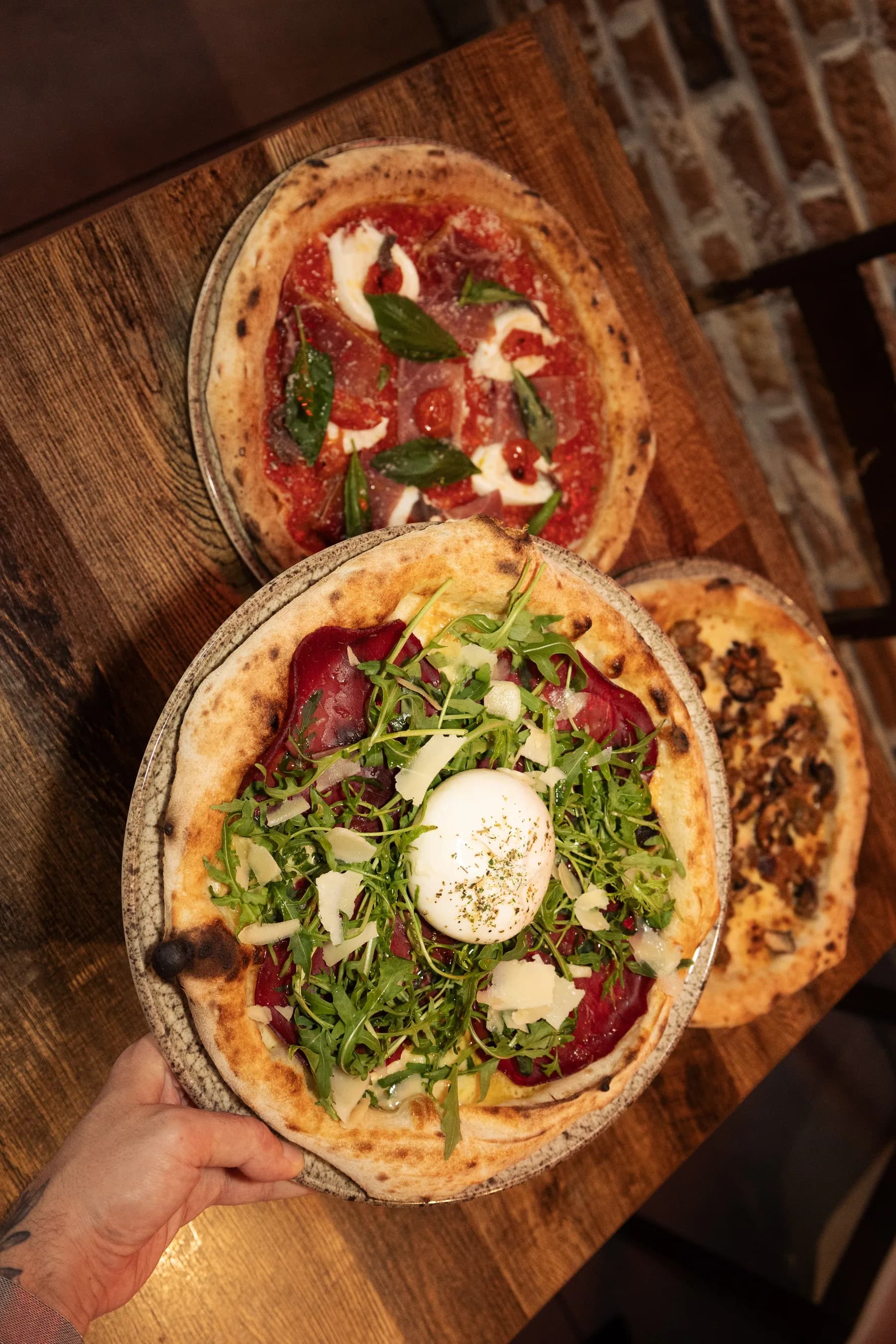 Overhead view of three Pizzerium pizzas being served